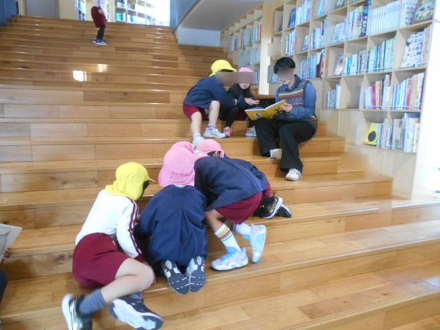広い階段に座ってみんなで絵本を見ています